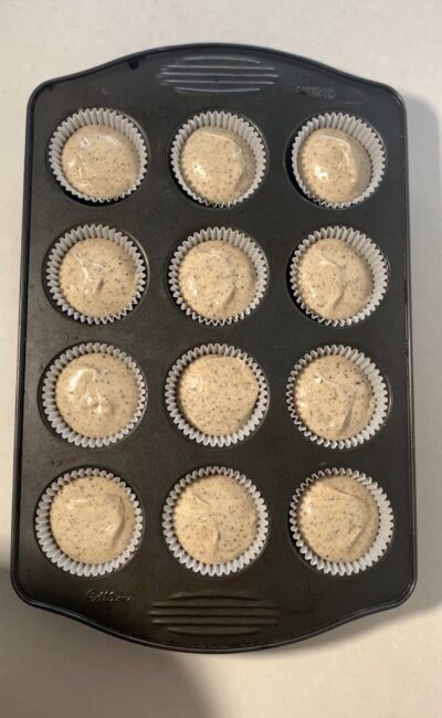12-cupcake tin with paper liners, Oreos, and batter. 