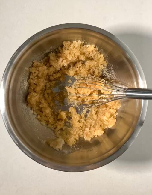 Oil and sugars (brown and granulated) in a large metal bowl, mixed. 