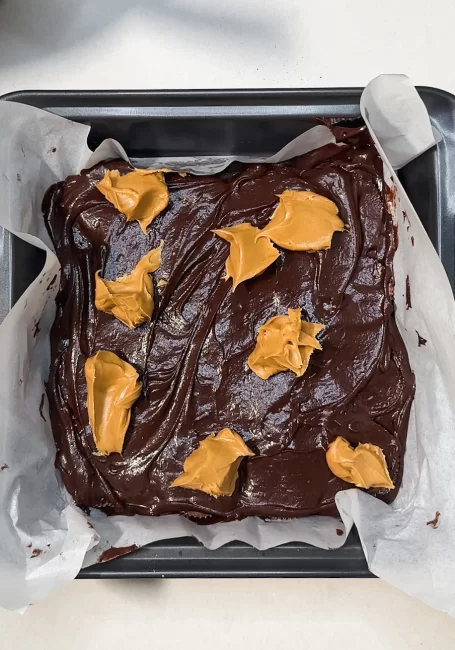 peanut butter dollops on peanut butter cup brownies 