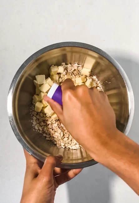 flour, sugars and oats in a bowl being mixed in a bowl