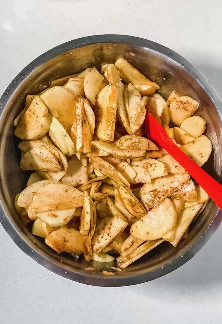 chopped apples with maple syrup, cinnamon, flour and lemon juice mixed in a large bowl