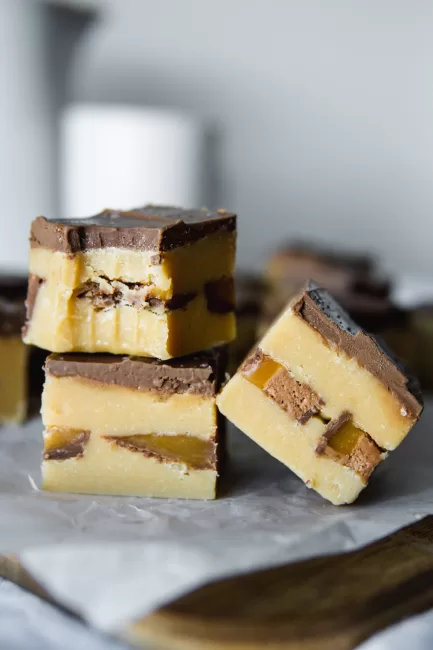 Chocolate Bar Fudge stacked together with a bite out of one piece