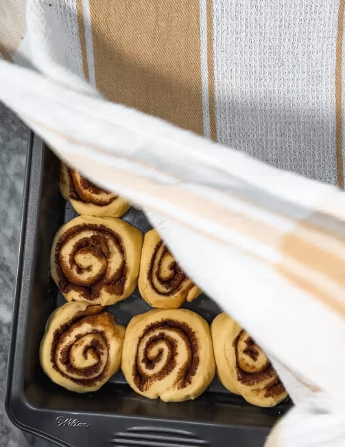 Homemade Cinnamon Rolls dough proofing under towel