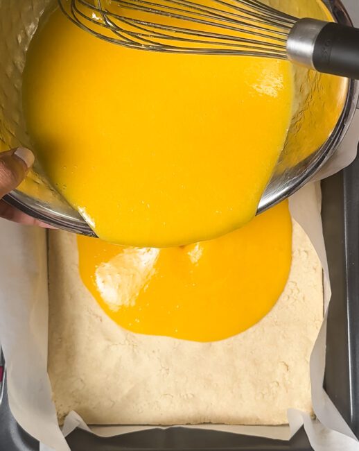 pouring mango lemon custard over shortbread crust