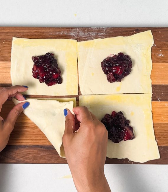 folding pastry over blueberry mango filling