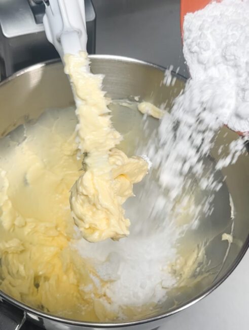 powdered sugar being added to mixed butter